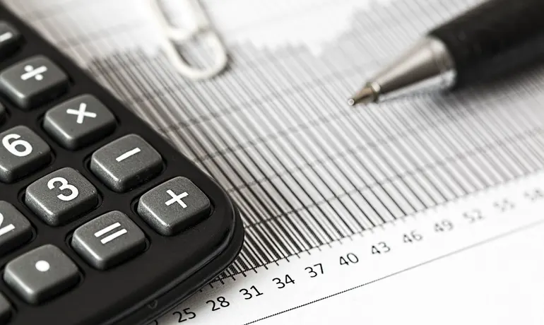 Calculadora e caneta sobre um relatório com gráfico de barras