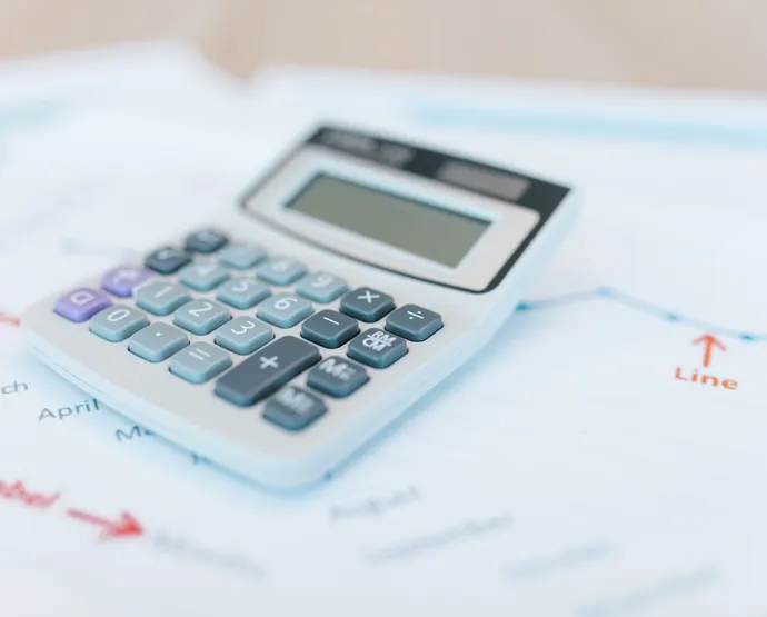Mesa com calculadora, caneta e relatórios financeiros